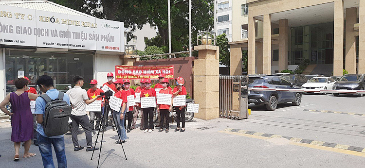 Cực chẳng đã, nhóm người lao động đại diện hơn 45 công nhân Công ty cổ phần khóa Minh Khai đành mang băng rôn, biểu ngữ đứng trước cổng toà nhà COMA