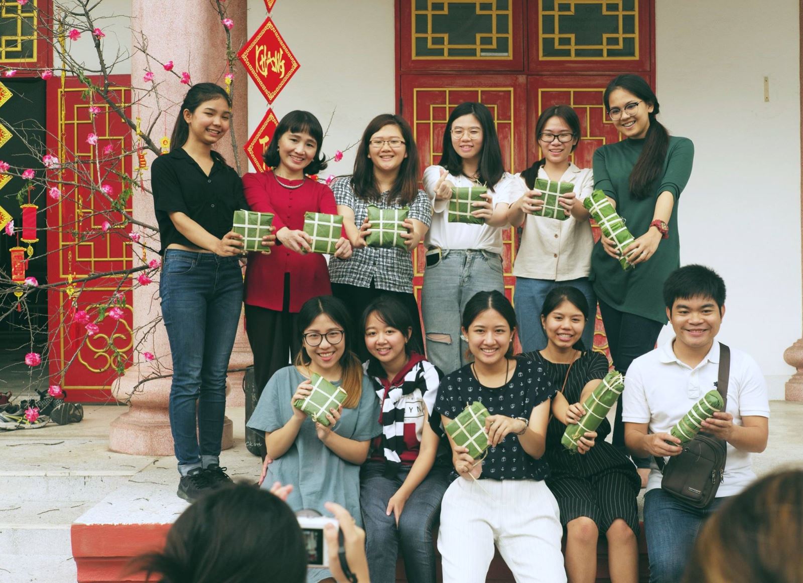 Chị Thúy Hà (áo đỏ) chụp ảnh lưu niệm cùng các sinh viên Việt Nam tại Thái Lan trong một buổi gói bánh chưng cộng đồng do Trung tâm VLK tổ chức.