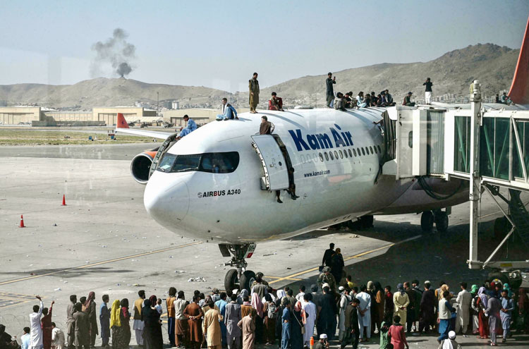 Cảnh tượng người Afghanistan đu bám và chạy theo một chiếc máy bay quân sự đang lăn bánh trên đường băng. (Ảnh: KT)