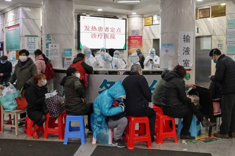 Bệnh nhân ngồi xếp hàng chờ trước một bệnh viện quá tải ở Vũ Hán. (Ảnh: Reuters)
