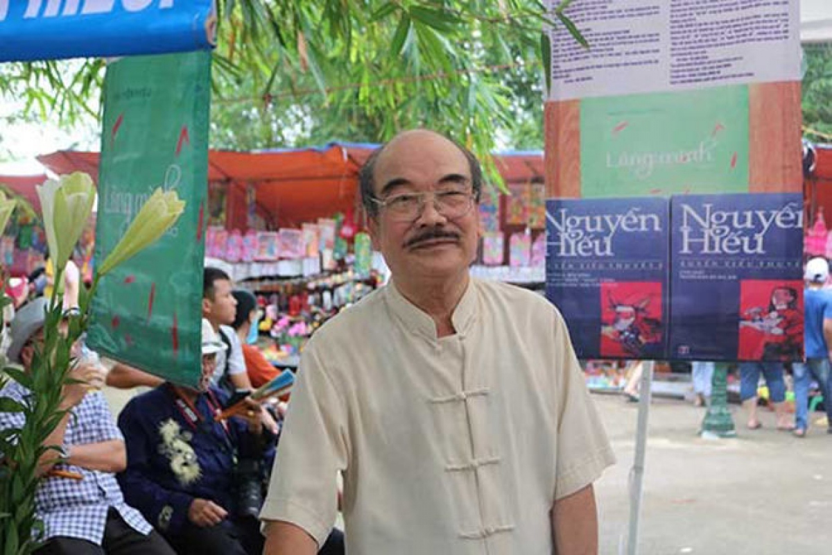 Nhà văn Nguyễn Hiếu bên quầy sách của mình ở hội làng Chèm. (Ảnh: Thuỷ Vũ)