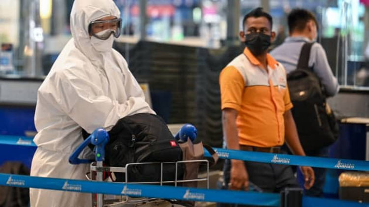 Một hành khách đeo thiết bị bảo hộ cá nhân xếp hàng để làm thủ tục cho chuyến bay tại Sân bay Quốc tế Kuala Lumpur ngày 29/11. (Ảnh: AFP)