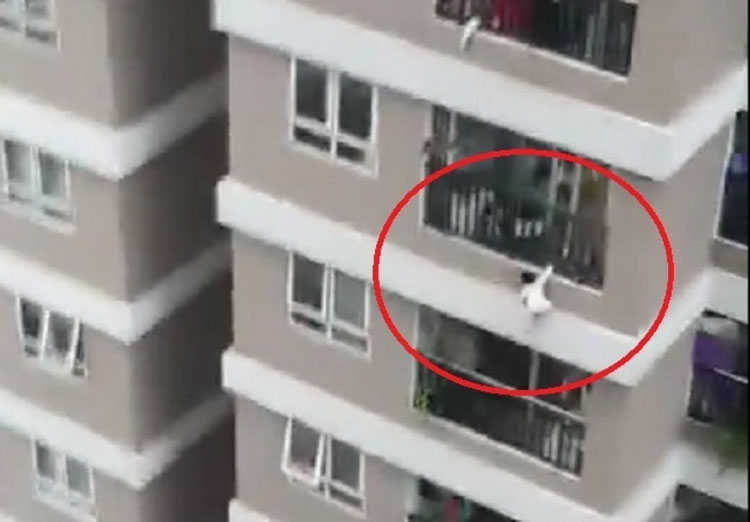 Hình ảnh bé gái treo mình trên lan can tầng 12A của chung cư. (Ảnh chụp màn hình).