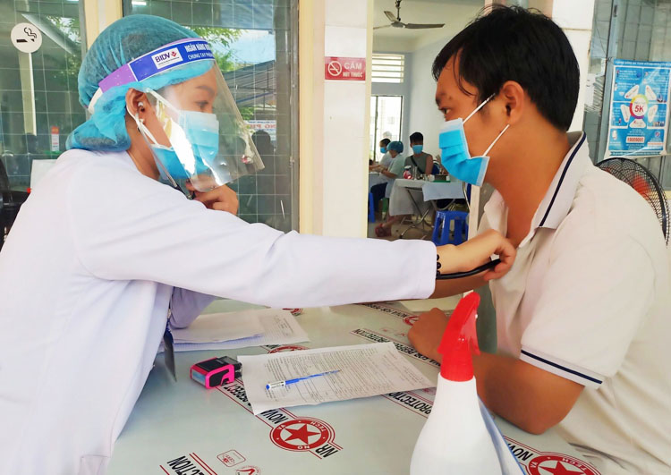 Cán bộ y tế tại Trung tâm Kiểm soát bệnh tật (CDC) tỉnh Cà Mau khám sàng lọc cho người tham gia tiêm chủng. (Ảnh: Ngọc Diễm)