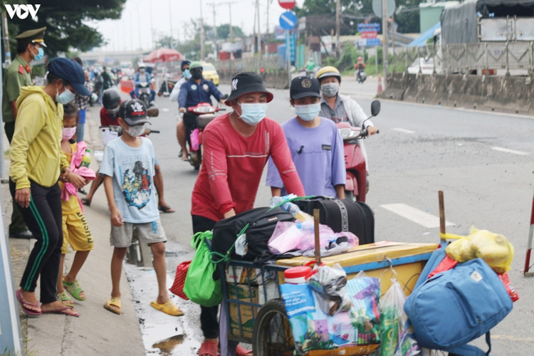 Một gia đình đi bộ, đẩy xe chất đầy hành lý về quê. (Ảnh: Tỷ Huỳnh, Lê Minh)