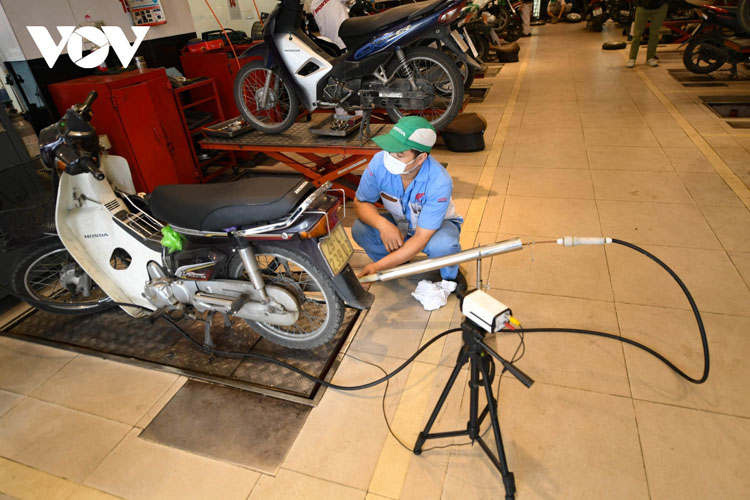 Nhân viên lắp đặt hệ thống đo kiểm khí thải xe máy.