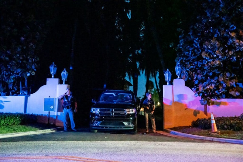 Đặc vụ FBI cầm súng trường đứng bên cạnh ô-tô, gác ở lối vào dinh thự Mar-a-Lago. (Ảnh: NYT)