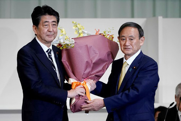 Ông Yoshihide Suga (phải) tặng hoa cho Thủ tướng Abe Shinzo sau khi được bầu làm chủ tịch Đảng Dân chủ Tự do hôm 14/9. (Ảnh: REUTERS)
