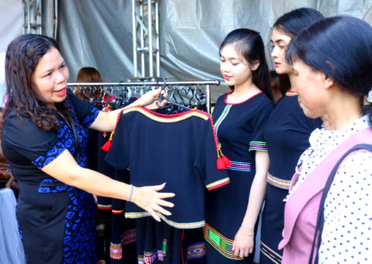 Chị H Ler Êban (bìa trái) giới thiệu sản phẩm trang phục cách tân tới khách hàng.