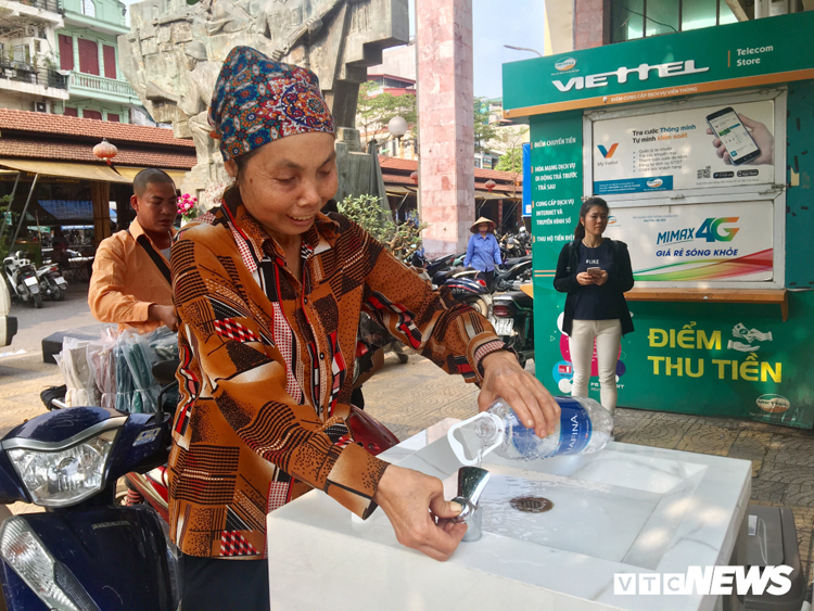 Một người bán hàng rong tại chợ Đồng Xuân đang lấy nước vào chai nhựa thay vì dùng trực tiếp tại trụ. (Ảnh: Thùy Ngân)
