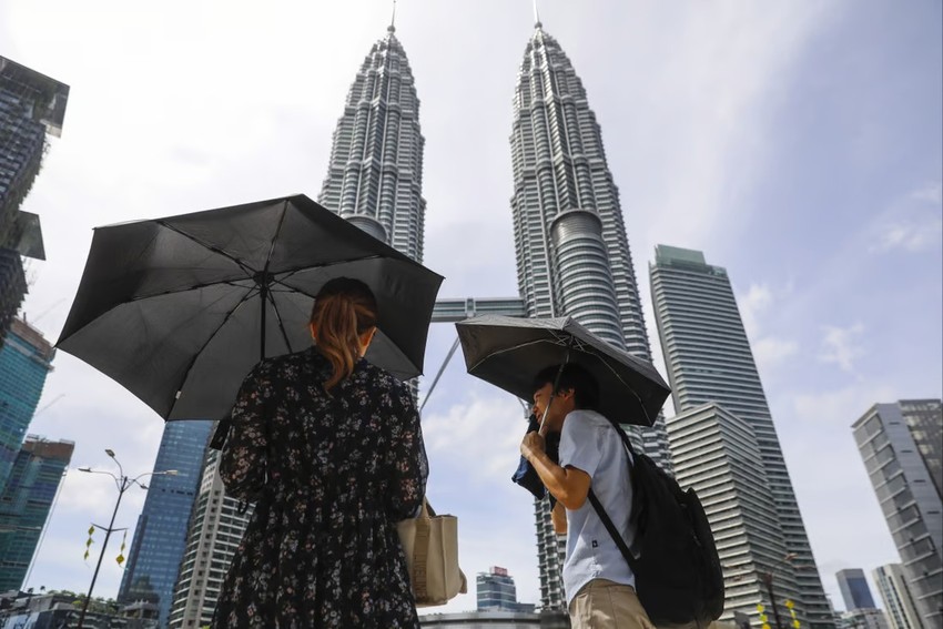 Người dân dùng ô để che nắng trong một ngày nắng nóng ở Kuala Lumpur (Malaysia) vào tháng 4. (Ảnh: EPA)