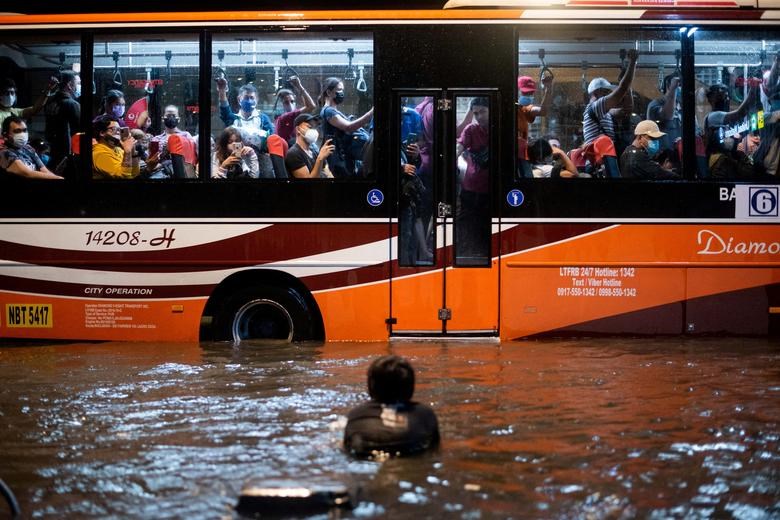 Một đứa trẻ bơi trong nước lũ do mưa lớn khi một chiếc xe buýt chở khách đi ngang qua, ở Manila, Philippines. (Ảnh: Reuters)