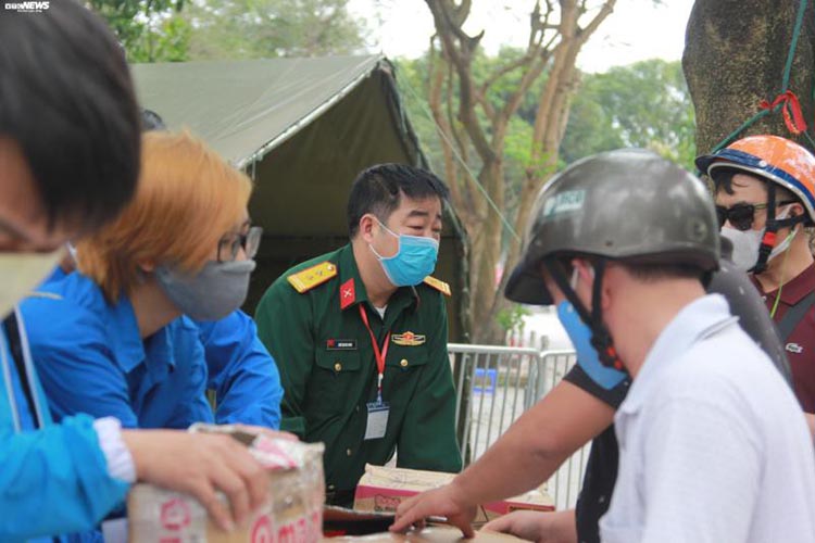 Trung tá Ngô Quang Dinh cùng các thanh niên tình nguyện giải thích cho người dân hiểu về quy định không được mang đồ ăn, thức uống vào trong khu cách ly.