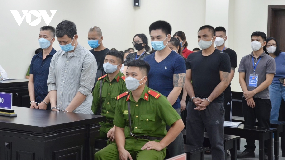 Bác sĩ Đỗ Thị Lưu (đeo kính, áo tối màu đứng hàng cuối) và 9 bị cáo khác trong phiên xử ngày 30/8. (Ảnh: Lam Lam)
