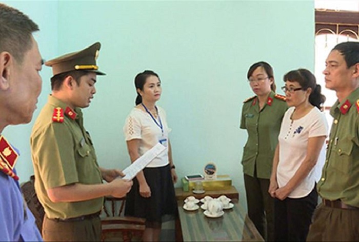 Bị can Nguyễn Thị Hồng Nga (áo trắng bên phải) nghe tống đạt quyết định khởi tố. 