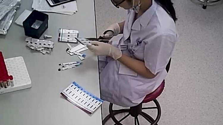 Nhân viên y tế cắt đôi que test HIV và viêm gan B. Ảnh: VTV24.