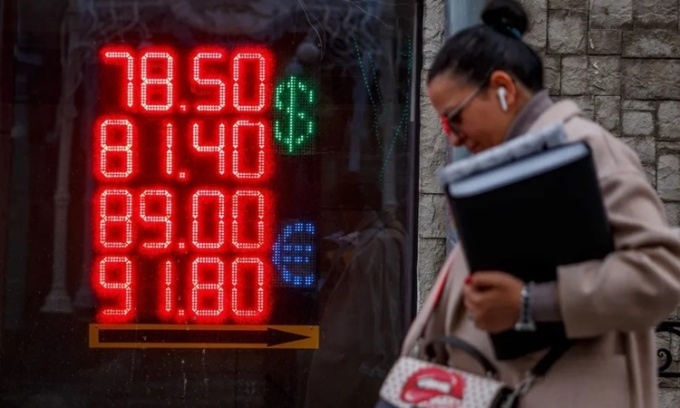 Người phụ nữ đi qua bảng điện hiển thị tỷ giá hối đoái giữa đồng USD và euro với đồng rúp của Nga ngày 22/2 ở Moscow. Ảnh: AFP.