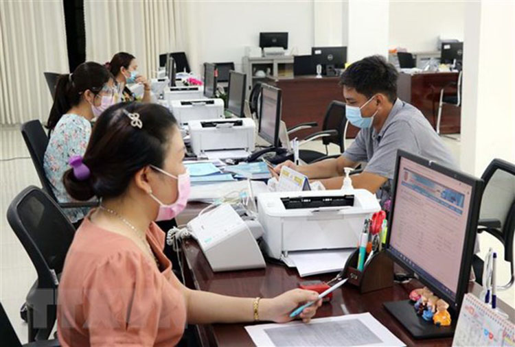 Cán bộ công chức Trung tâm Phục vụ hành chính công tỉnh Ninh Thuận giải quyết hồ sơ, thủ tục hành chính cho các doanh nghiệp. Ảnh: TTXVN