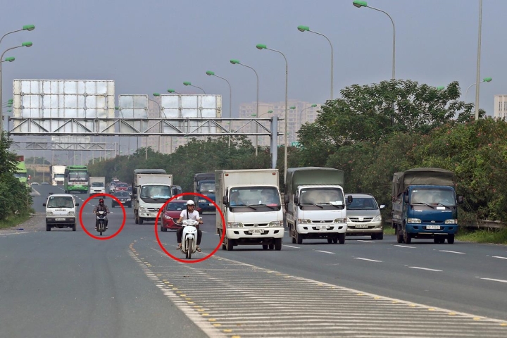 Nhiều người bất chấp lệnh cấm vẫn lái xe máy vào làn cao tốc chỉ dành cho ô tô trên Đại lộ Thăng Long.