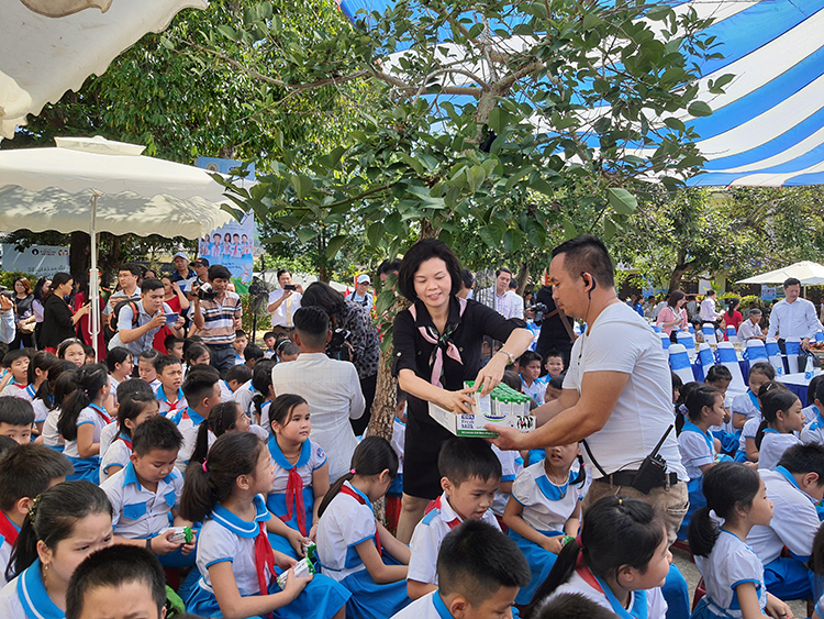 Các em học sinh trường Kim Đồng nhận những hộp sữa từ Vinamilk và các đại biểu tham dự chương trình.