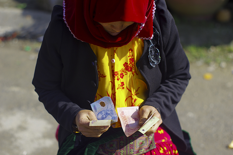 Người phụ nữ đếm những đồng tiền bán được ở chợ.