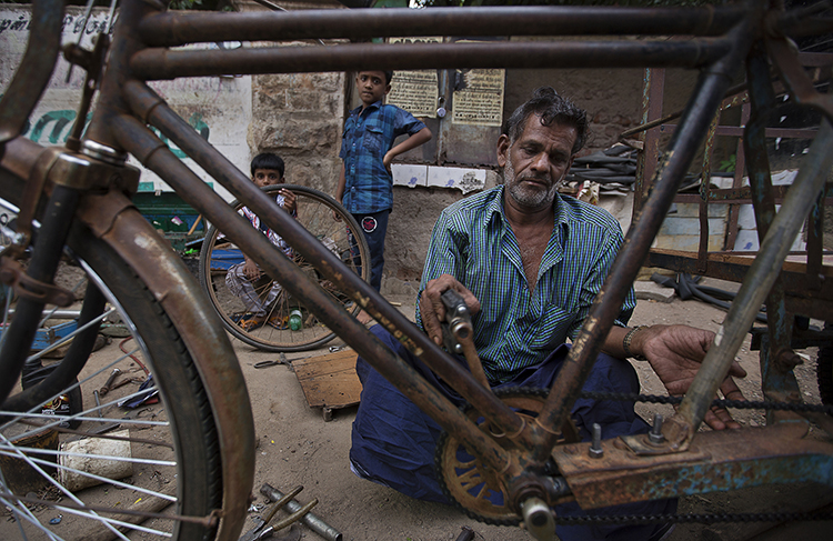 Một người đàn ông sửa xe đạp trên đường phố, những mẫu xe đạp rất thịnh hành ở Madurai mà chúng ta thường bắt gặp ở thập niên 70-80 tại Việt Nam.