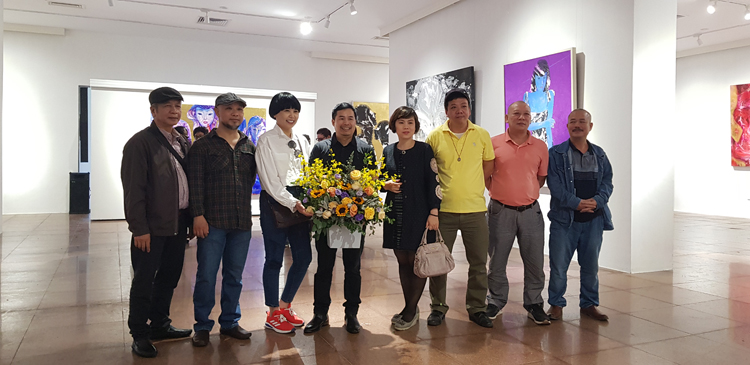 Họa sĩ Nguyễn Lương Huyên (người ôm hoa) trong ngày khai mạc triển lãm.