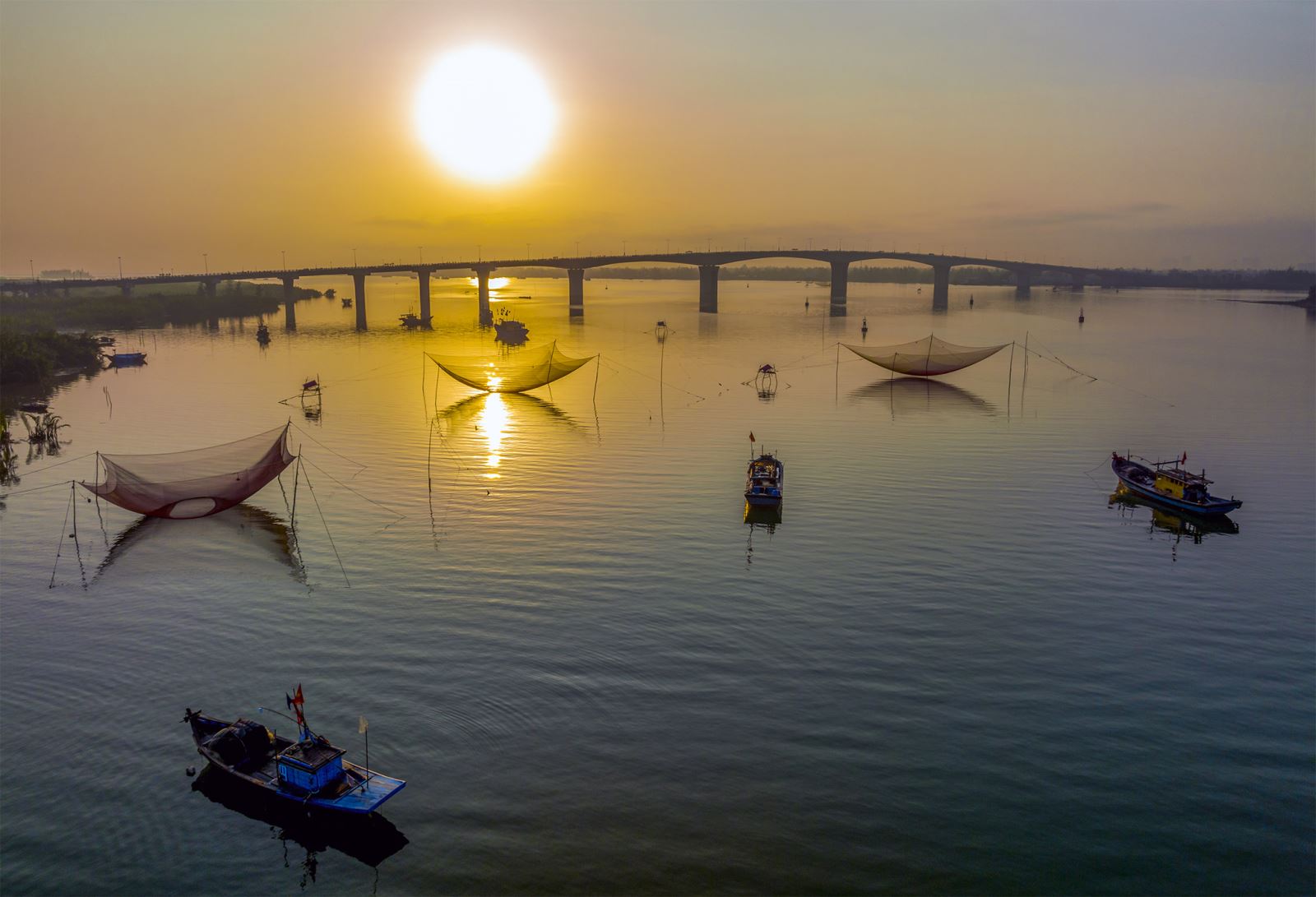 Cầu Cửa Đại là cây cầu dài nhất ở Quảng Nam đến thời điểm này, nhịp chính dài gần 1,5km nối liền Hội An và Duy Xuyên giúp cuộc sống. Phía xa xa là xã đảo Tân Hiệp - Cù Lao Chàm.